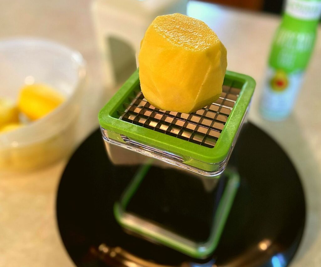 A potato about to be cut with a french fry cutter.