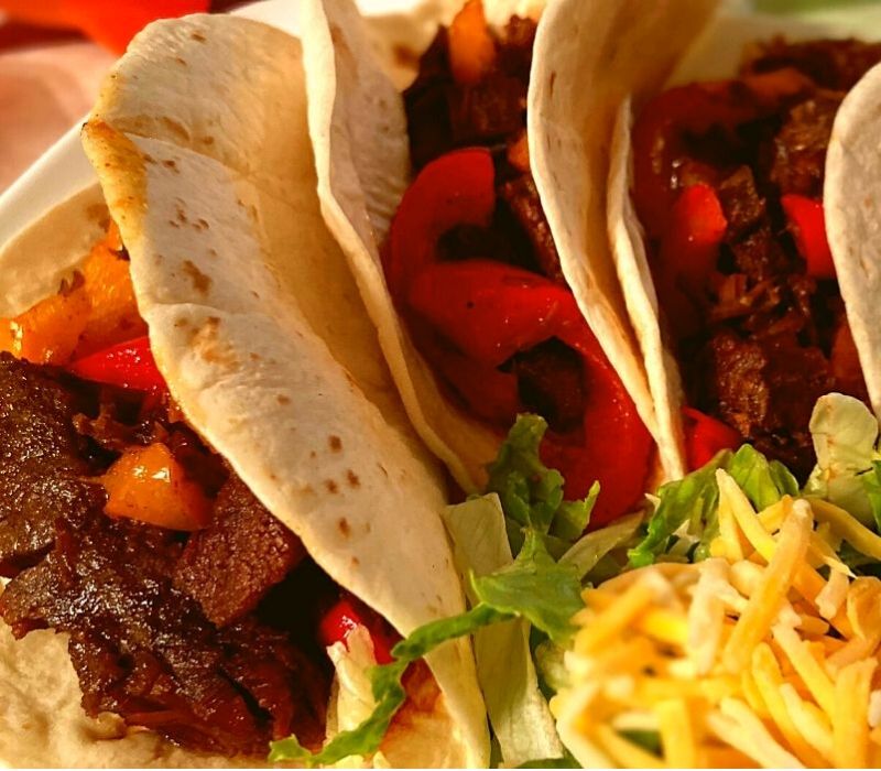 Instant Pot Fajitas on a plate with shredded lettuce and cheese.