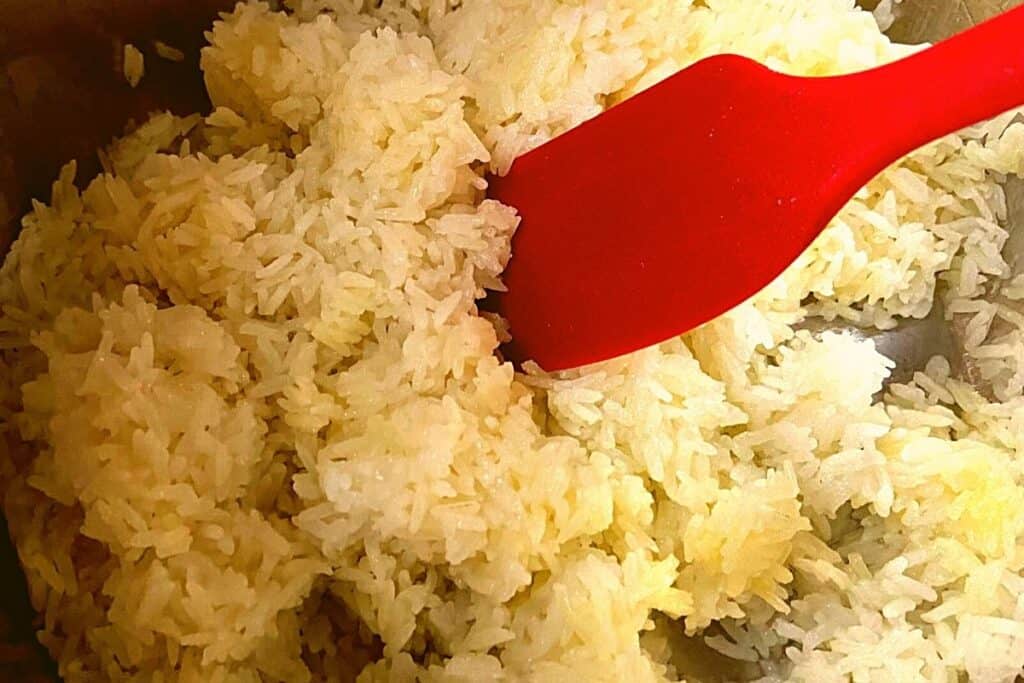 cooked jasmine rice being fluffed with a spatula in a instant pot