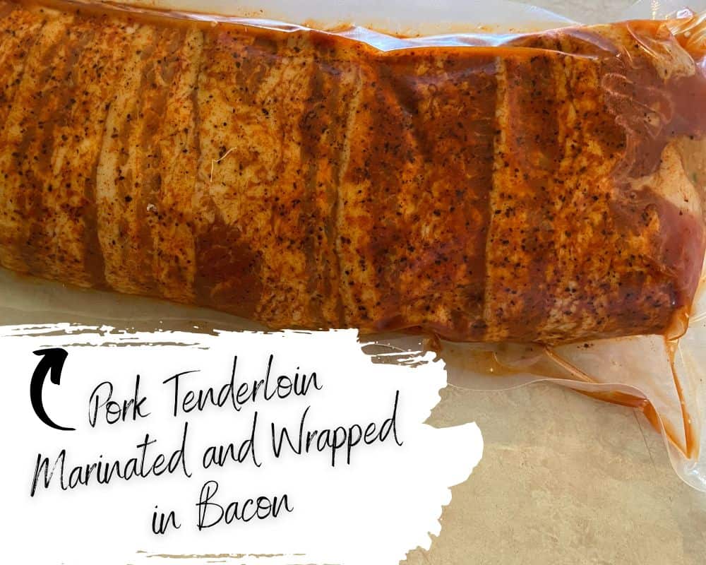 A raw, marinated pork tenderloin wrapped in bacon