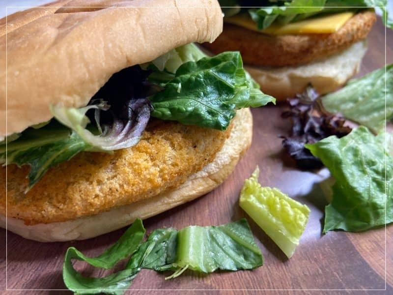 2 cooked chicken patties in hamburger buns on a plate with lettuce