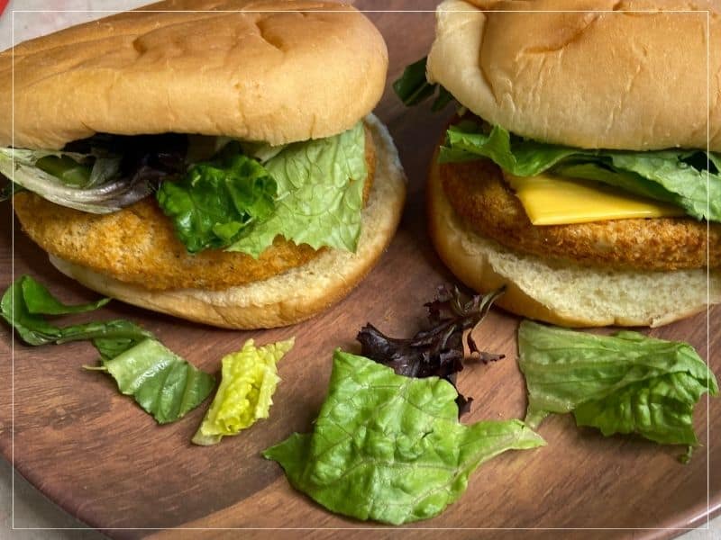 2 frozen chicken patties after being cooked in an air fryer. Sitting on a plate in hamburger buns